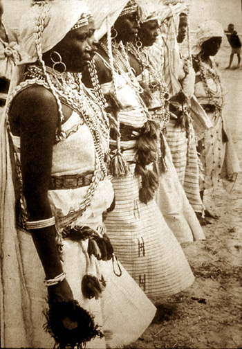 women in white adorned with cowries and other regalia