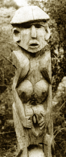 rough wooden carving of a woman holding open her vulva