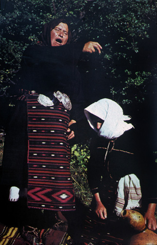 folk healer chanting and sprinkling medicine on a crouching woman